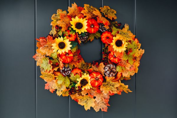 Autumn wreath with sunflowers, pumpkins and maple leaves on front door