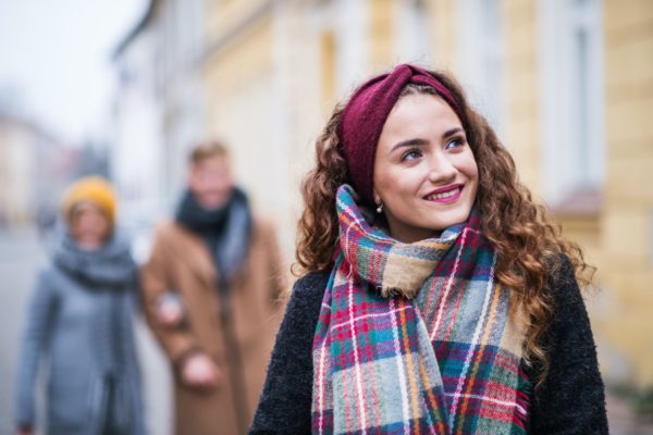 A portrait of teenage girl with headband and scarf on the street in winter.