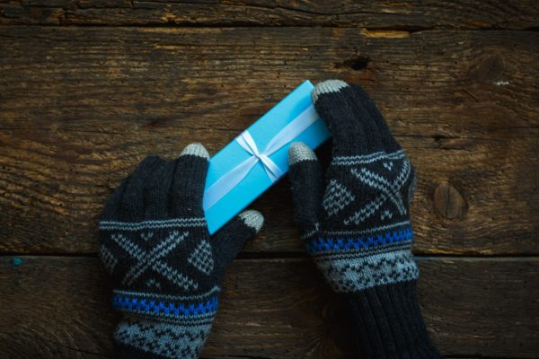 Hands in winter gloves with christmas gift box