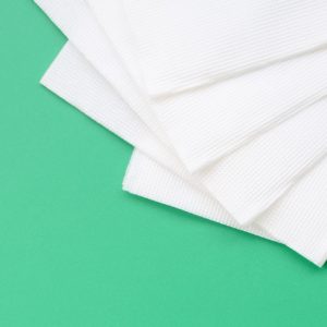Several white paper napkins lie on a plastic green background