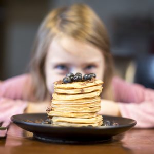Plate with stack of pancakes with little girl in the background